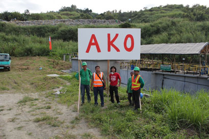 Four guys are standing along with the sign AKO.