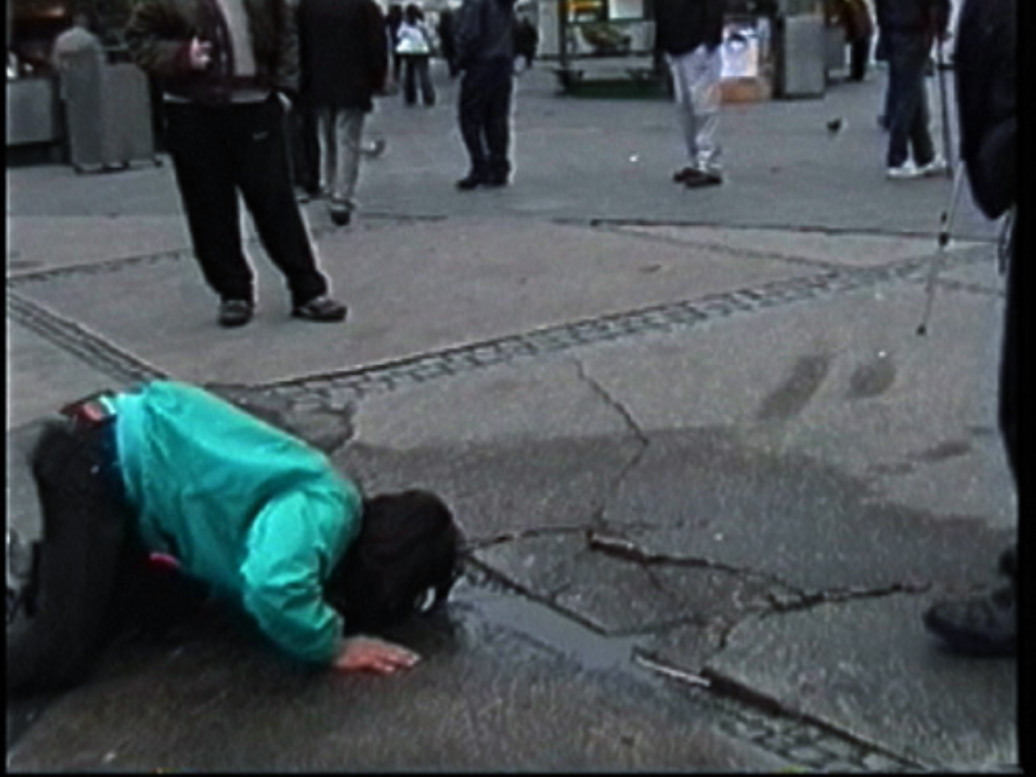The artist is drinking water on the street in the former east Berlin.