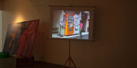 A small video projection that showing the artist is putting coins into a vending machine.
